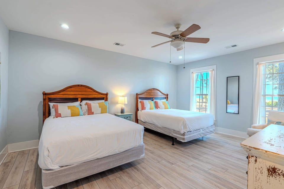Twin queen beds with warm wood headboards and coastal hues await at 152 Ave of Oaks — your Hilton Head Island retreat where sunlit mornings and effortless relaxation begin.