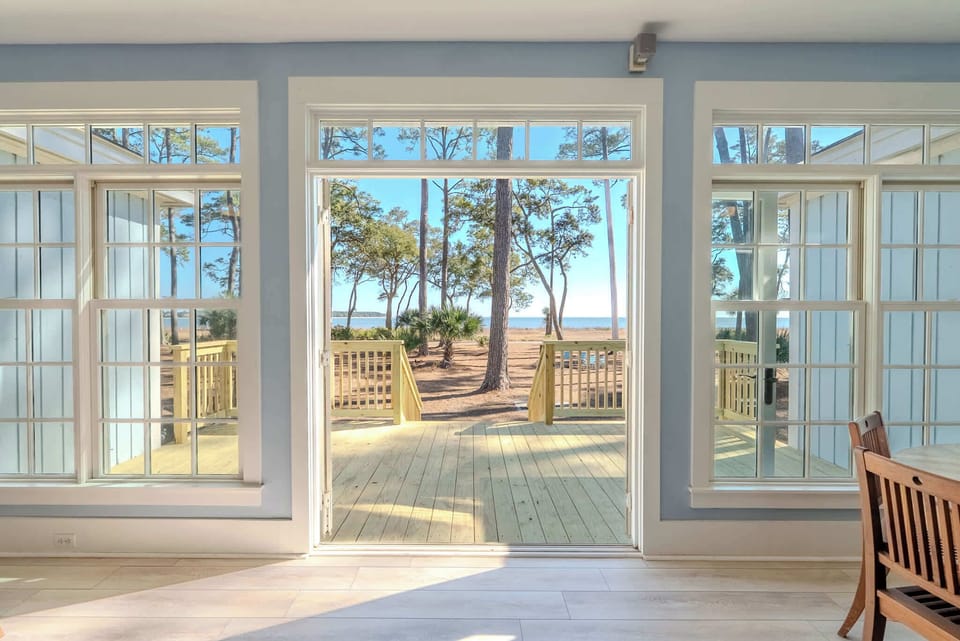 Step through French doors into coastal serenity — where longleaf pines frame breathtaking Calibogue Sound views from your private waterfront deck at 152 Ave of Oaks, Hilton Head's hidden gem.