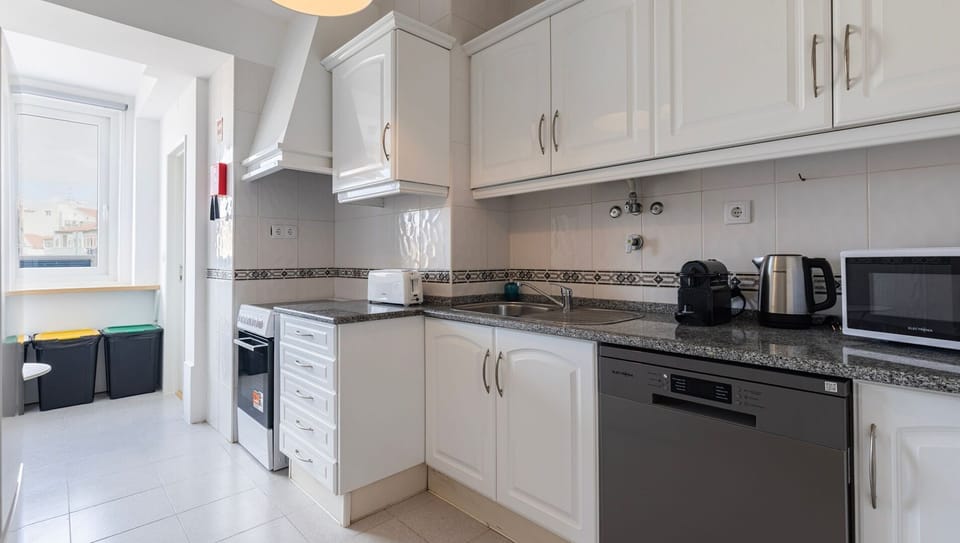Cook up a storm in the fully equipped kitchen featuring modern appliances, ample counter space, and a sunny balcony for natural light. #LisbonApartment #FullyEquippedKitchen #CityStay #LovelyStayPortugal