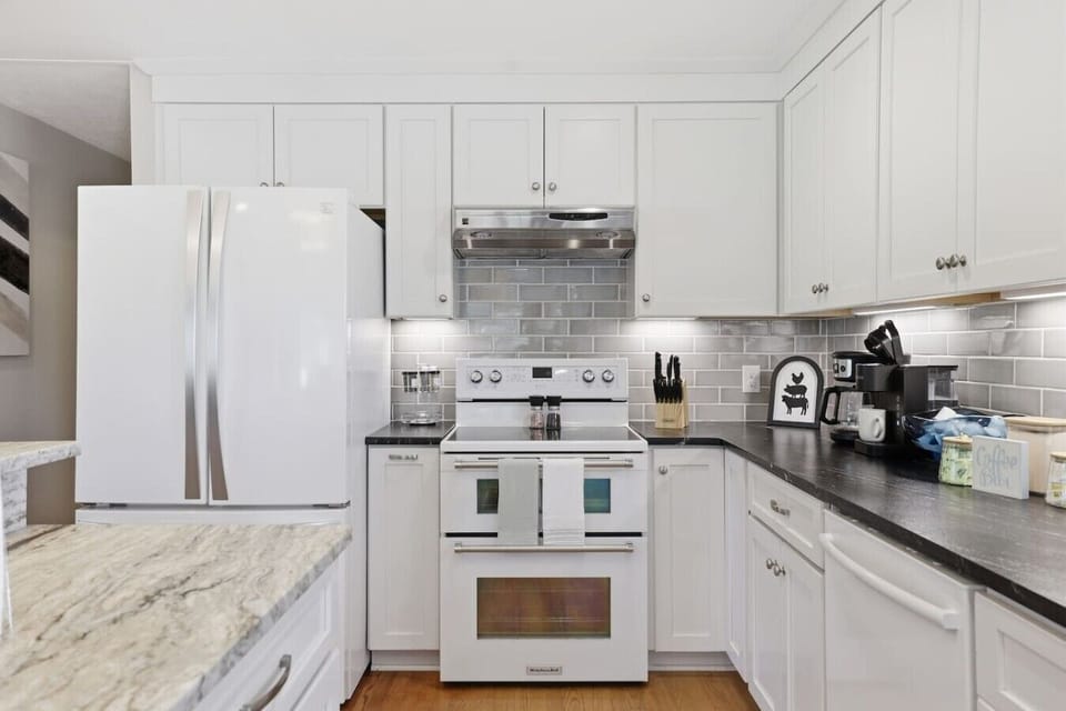 Modern, fully equipped kitchen with sleek finishes, island seating, extra bar space, double door fridge with freezer and a dedicated coffee nook—bright, stylish, and perfect for effortless meals.