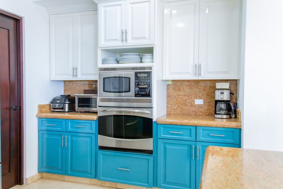 Bright kitchen with double ovens, microwave, and vibrant blue cabinetry.
