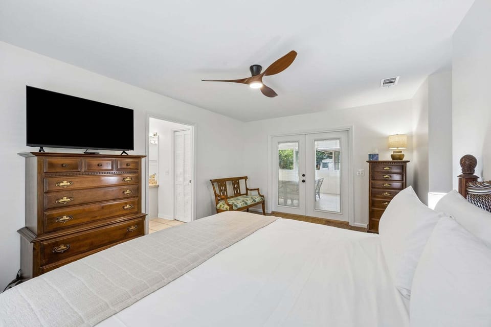 Primary bedroom with king bed, tv, dressers, ensuite bathroom and direct access to screened-in back porch