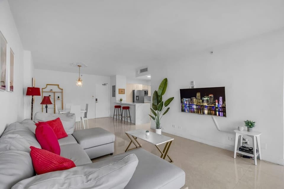 Bright and stylish living room with plush seating, Smart TV, and floor-to-ceiling windows with stunning bay views