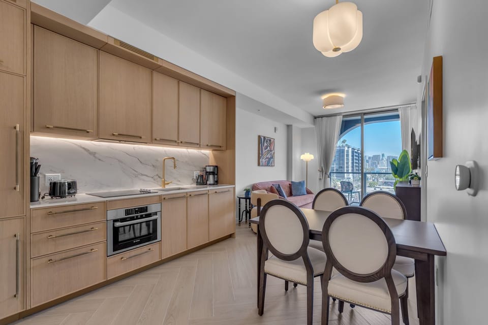 Open-concept kitchen and dining area with premium appliances, warm wood cabinetry and a stylish dining set — perfect for meals in