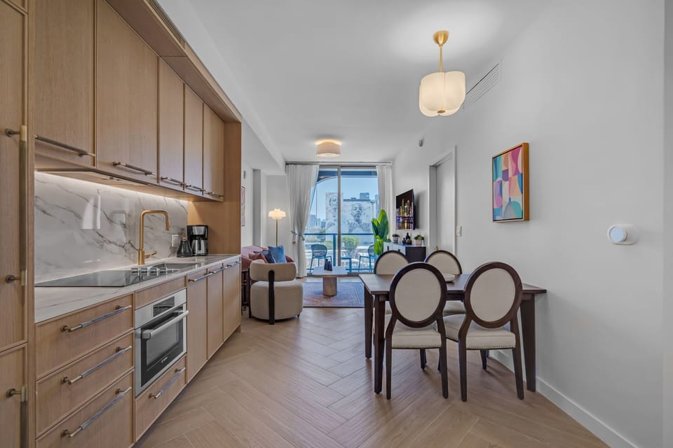 Elegant in-unit dining area with designer chairs, warm wood cabinetry and stylish pendant lighting — perfect for intimate meals at home