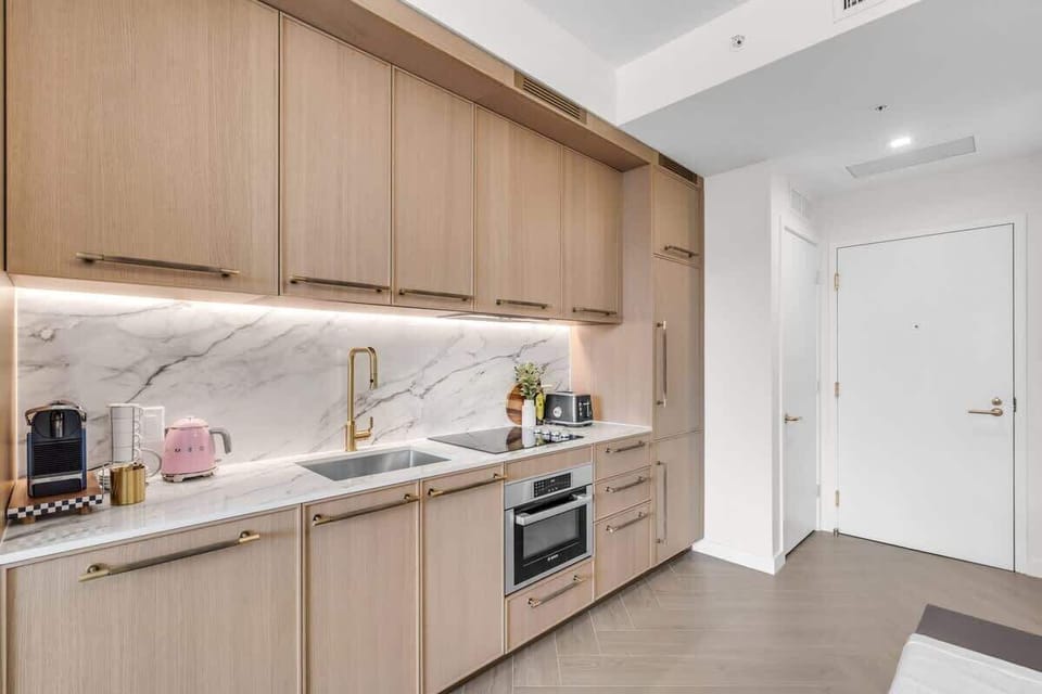 Sleek modern kitchen with warm wood cabinetry, quartz countertops, built-in appliances and gold fixtures — beautifully designed for cooking in style