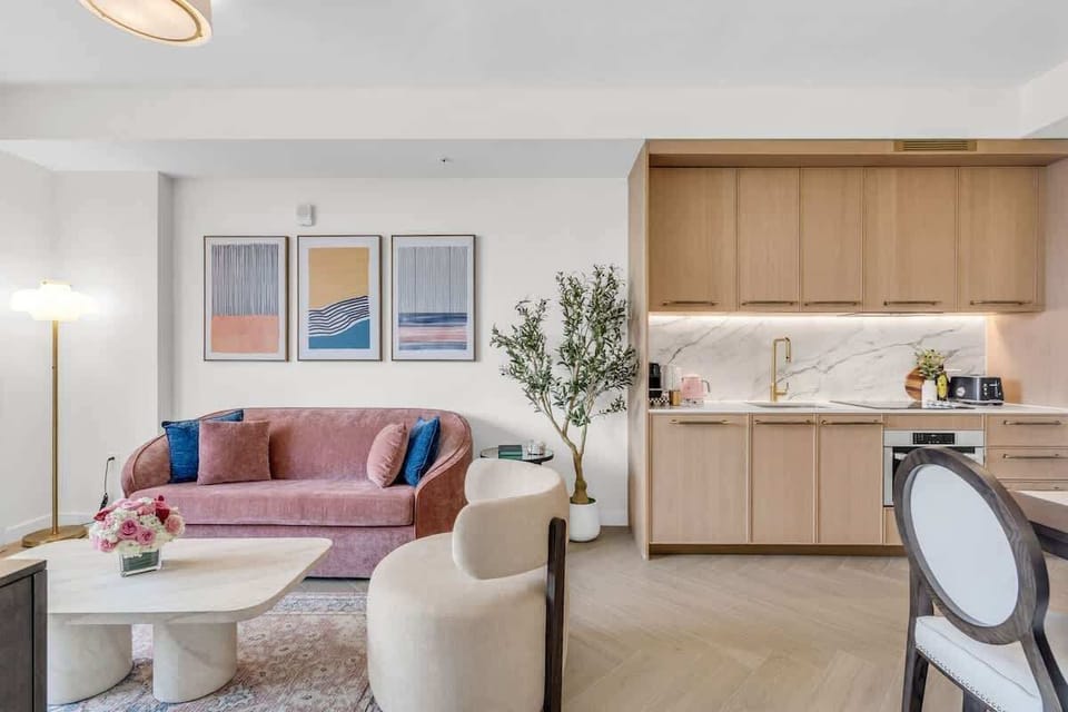 Open-concept living room with designer furnishings, curated artwork, and a seamless flow into the kitchen — bright, modern and welcoming