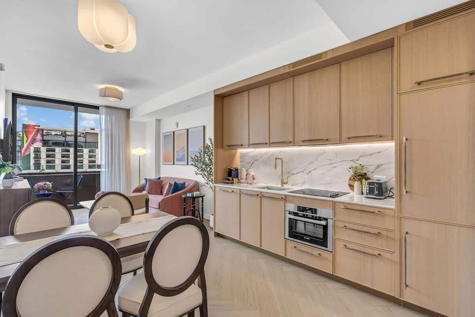 Open-concept kitchen and dining area with premium appliances, warm wood cabinetry and a stylish dining set — perfect for meals in