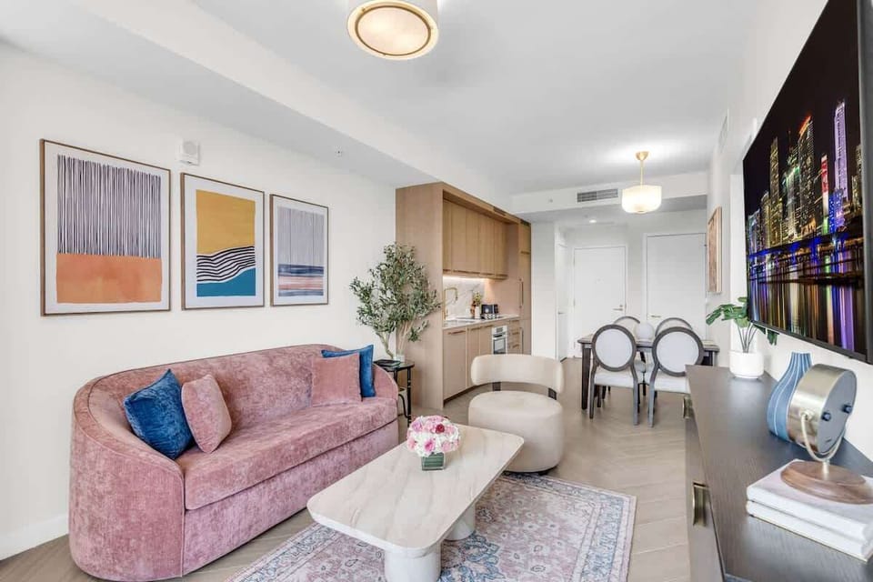 Elegant living room with plush pink velvet seating, curated art gallery wall, Smart TV and designer coffee table — sophisticated and inviting