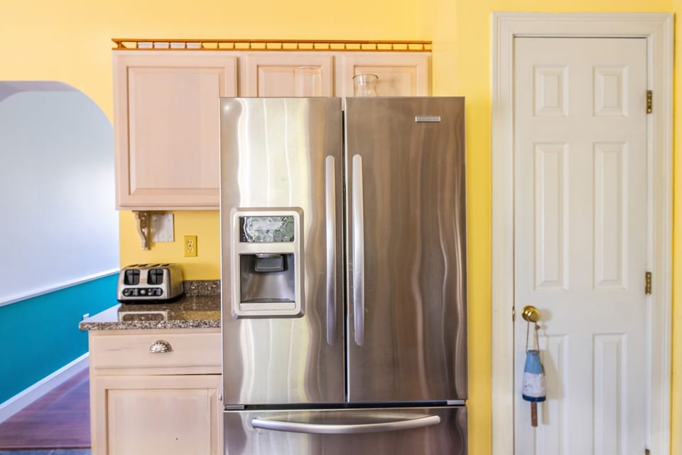The kitchen features a large stainless steel Frigidaire refrigerator with an exterior ice and water dispenser. Stock up on local Maine ingredients for your stay, with plenty of room for group groceries and a 4-slice toaster for easy morning breakfasts.