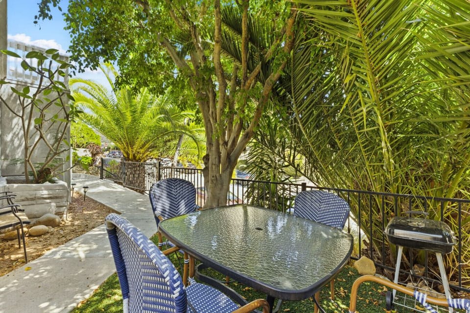 Enjoy al fresco dining beneath the palms on the secluded patio, featuring a dining table and grill for memorable outdoor meals.