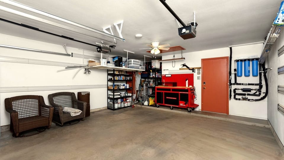 Spacious attached garage with ceiling fan, built-in shelving, overhead storage, and an automatic door opener — offering secure parking and generous additional storage for longer-term guests.
