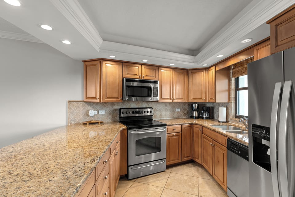 Cook with ease in the full kitchen featuring granite counters, stainless steel appliances, and bar seating.