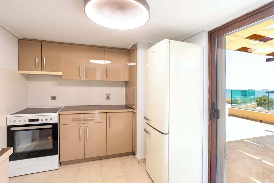 The secondary kitchen opens directly toward the terrace and outdoor lounge spaces, making rooftop meals and relaxed evenings feel completely natural.