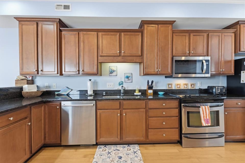 Your fully equipped kitchen features polished granite counters, warm wood cabinetry, and modern stainless steel appliances—perfect for crafting home-cooked meals or morning coffee.