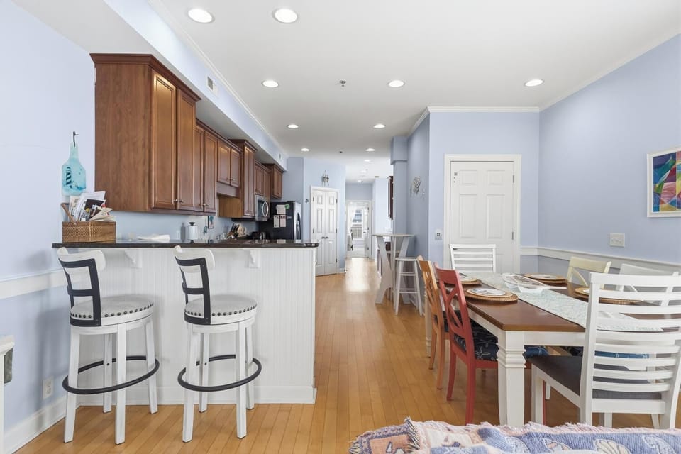 Gather around the open kitchen and dining area, where you'll find plenty of space to share meals and make memories together. Warm wood tones, bright lighting, and colorful seating create a welcoming spot.