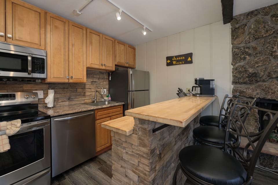 Your rustic-modern kitchen blends warm wood cabinets with stone accents, offering full appliances and breakfast bar seating for memorable meals.