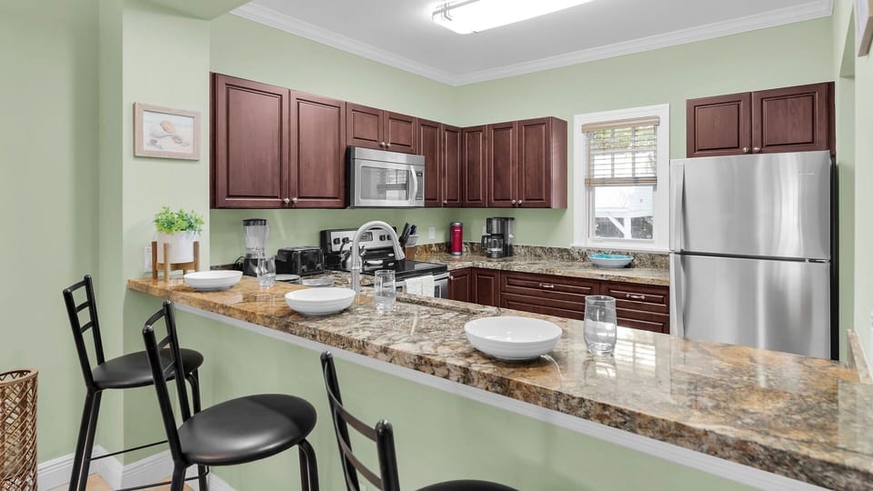 Your fully equipped kitchen awaits with granite counters, rich wood cabinetry, and stainless steel appliances. Gather at the breakfast bar for morning coffee or casual meals.
