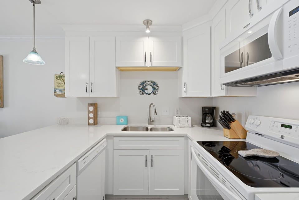 Grand Caribbean 305W- Your bright, fully-equipped kitchen features pristine white cabinetry, modern appliances, and all the essentials you'll need to whip up a delicious meal or morning coffee during your stay.