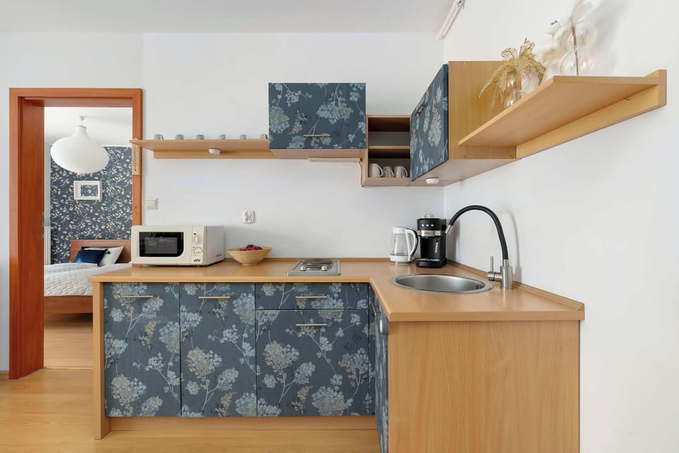 A functional kitchenette with wooden countertops and lower cabinets decorated with a blue floral pattern.