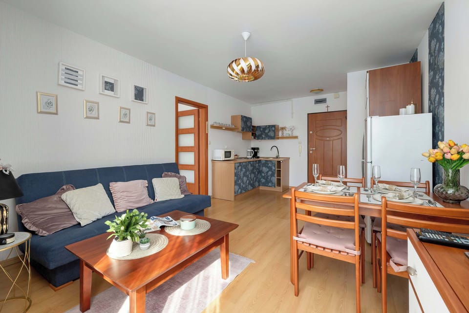 An open-concept living space with a dining area, a sofa, and a kitchen visible in the background.