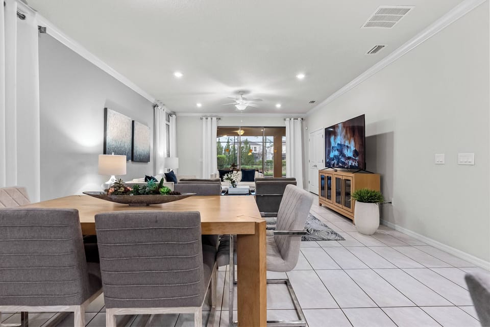 Enjoy meals and gatherings in this stylish dining area featuring a wooden table and contemporary gray chairs. Large windows fill the space with natural light, creating a bright, airy atmosphere that connects you to the outdoors.