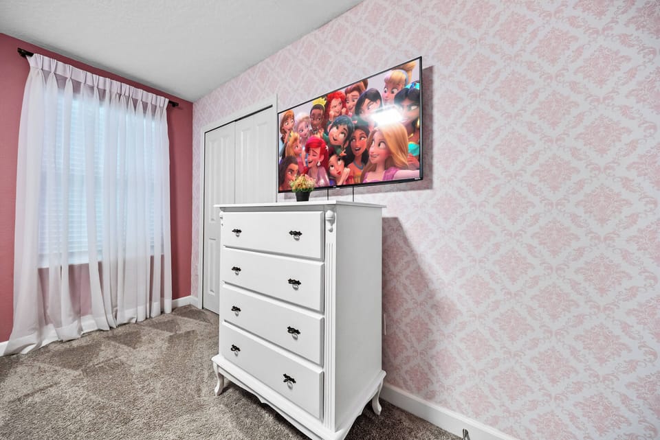 This cozy bedroom invites relaxation with a stylish white dresser and vibrant TV, perfect for unwinding after your adventures. Soft natural light filters through sheer curtains, enhancing the warm, welcoming atmosphere created by.