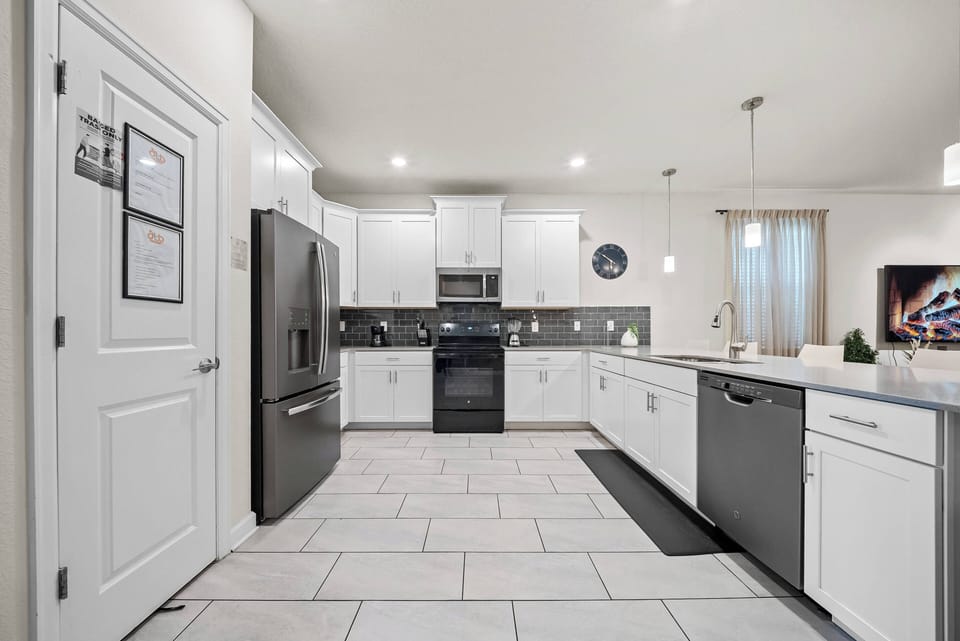 Welcome to this stylish kitchen, where white cabinetry meets dark appliances. The spacious layout and ample natural light create an inviting atmosphere, making cooking a delightful experience in this well-equipped area.