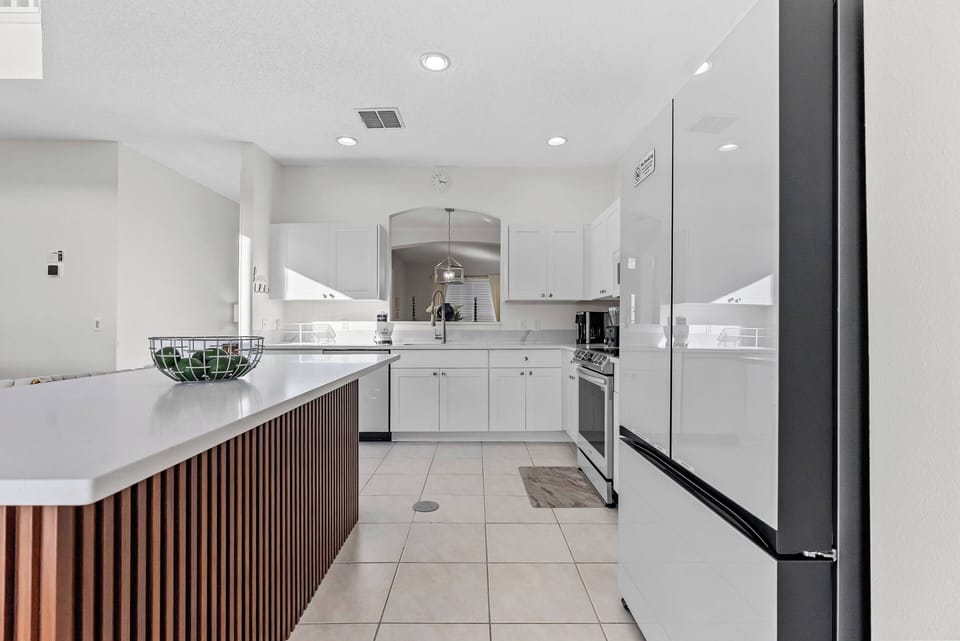 Discover a beautifully designed kitchen with sleek white cabinetry and a warm dark wood island. Bright natural light highlights modern appliances and a spacious layout, creating an ideal space for your culinary adventures.