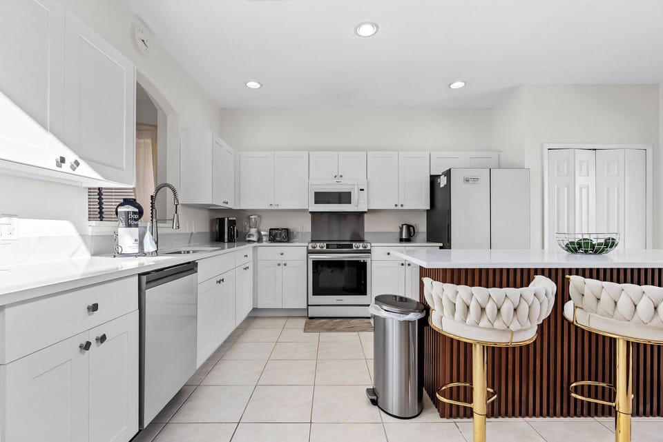 Bright and functional, this kitchen features sleek white cabinetry paired with granite countertops, creating a fresh ambiance. The inviting bar stools add a touch of warmth, perfect for casual breakfasts or late-night chats.