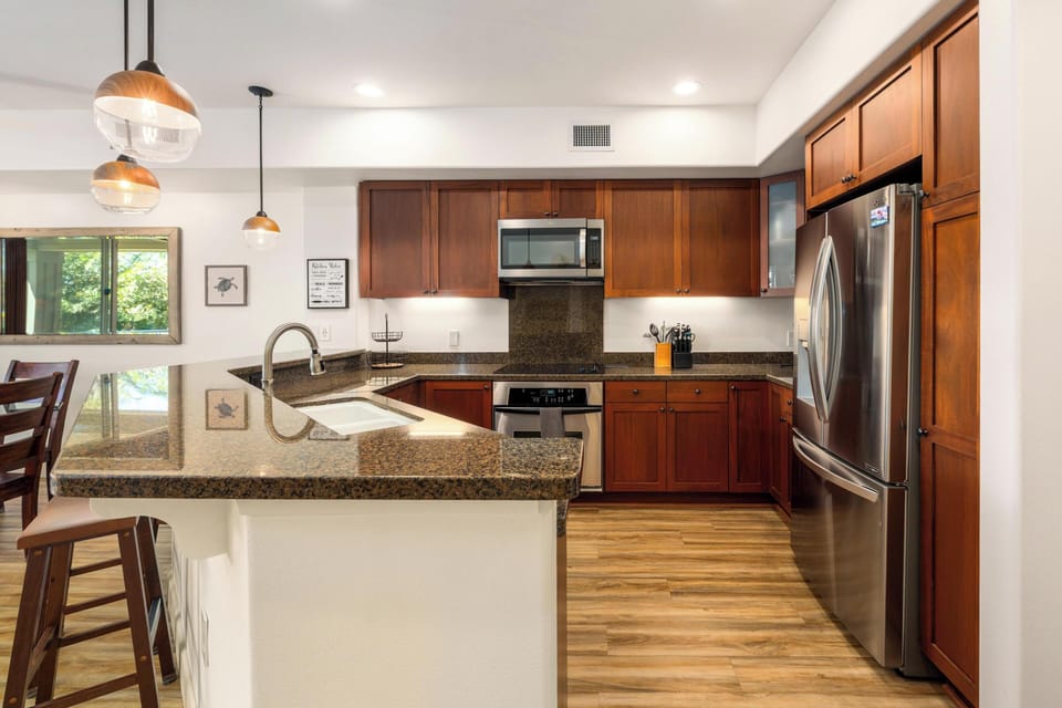 Your fully equipped kitchen features stainless steel appliances, granite countertops, rich wood cabinetry, and an island perfect for preparing your favorite meals during your stay.