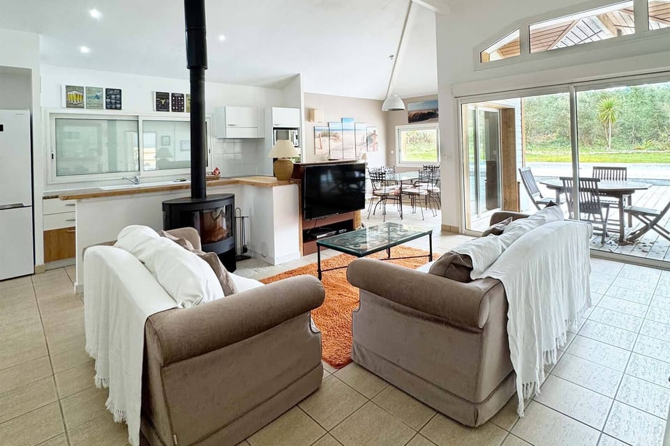 Open-plan living area, kitchen visible in background, sofa, tiled floors, bright space:<br>The bright open-plan living and kitchen area sets the tone — fully renovated and ready to welcome your whole group.
