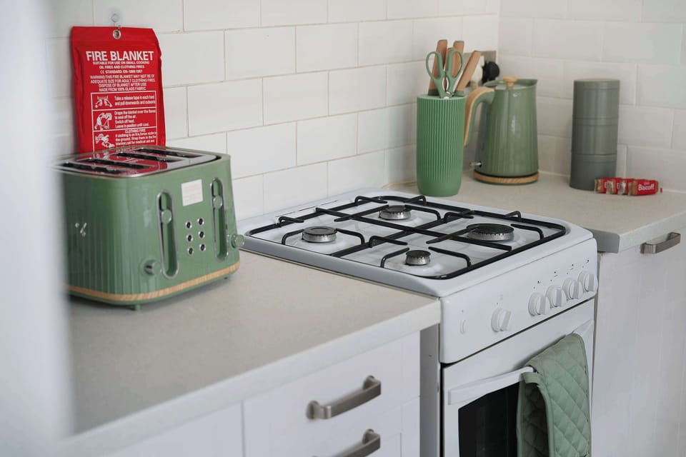 Well-organized kitchen offering a standalone cooker, fridge freezer, toaster, and laundry facilities. The practical setup is ideal for everyday use, providing everything needed for meal preparation along with convenient access to the back entrance.