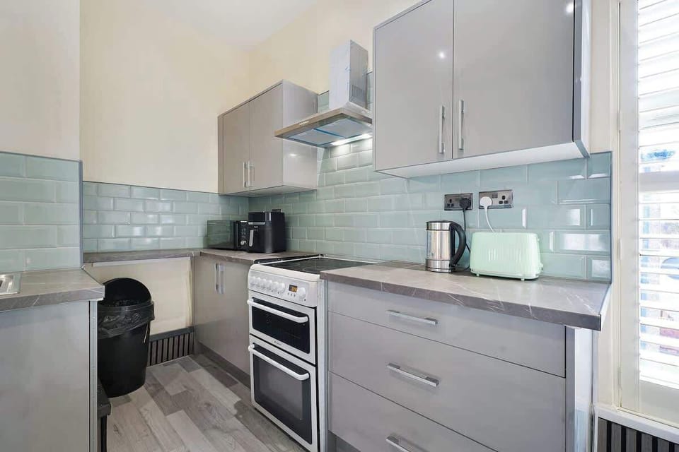 Everything you need for convenient meal preparation can be found in this well-equipped kitchen. Featuring a microwave, oven, air fryer, washing machine, sink, and fridge freezer, it offers a practical setup for daily living.