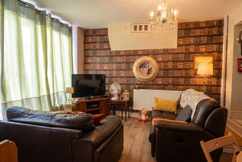 Whole lounge view with twin leather sofas and literary backdrop.