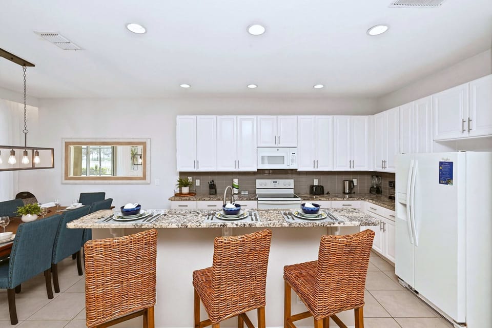 Open kitchen space with island counter and high chairs for cooking, dining, and casual group gatherings