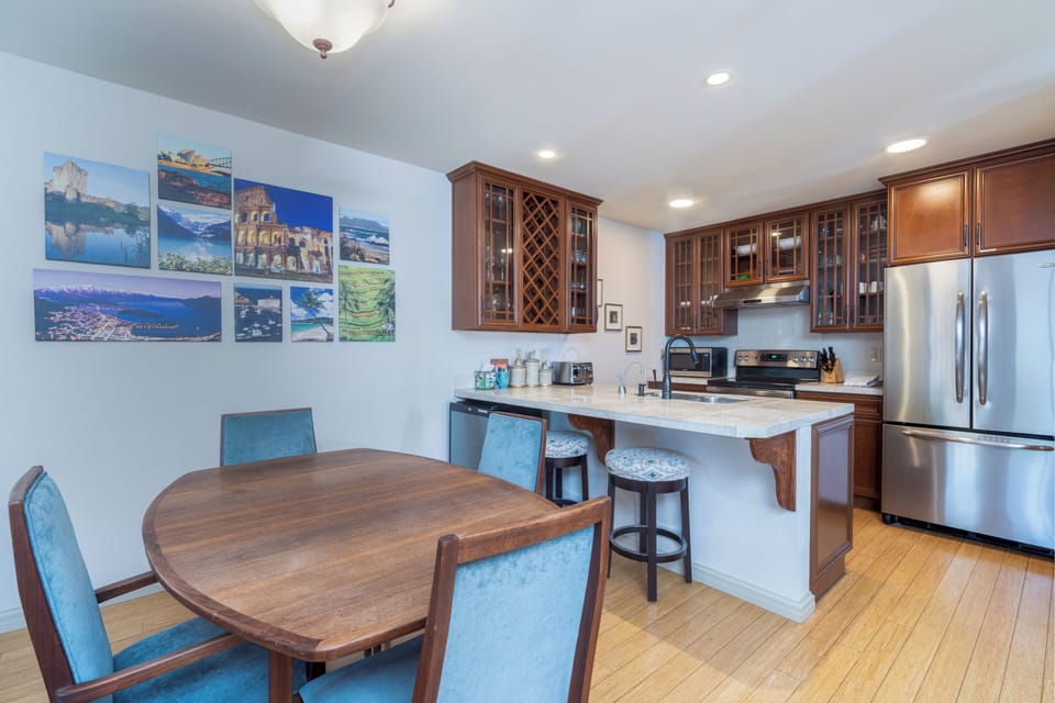 Picture yourself preparing meals in this welcoming kitchen with rich wood cabinetry, granite countertops, and stainless steel appliances. The breakfast bar invites casual dining while warm hardwood floors and scenic wall art add homey charm.