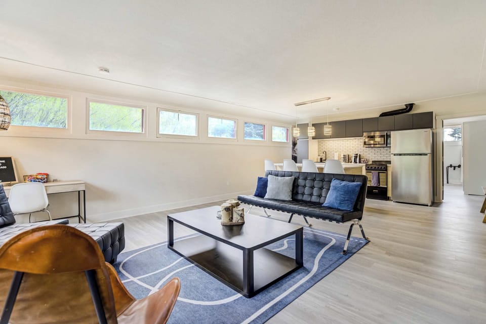 Rows of horizontal clerestory windows flood the living space with natural light, framing views of mountain greenery. A dedicated workspace with pendant lighting adds functional versatility for remote work or trip planning.