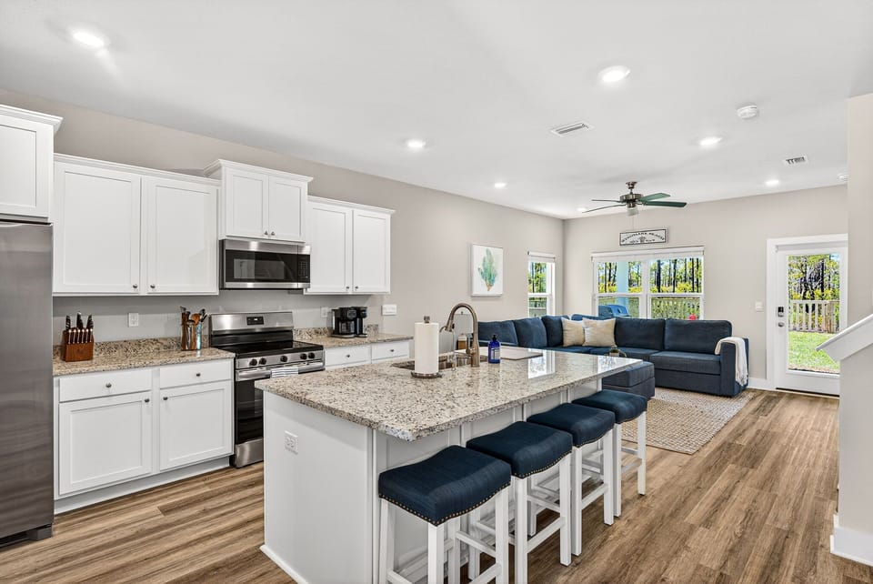 This bright, open-concept space blends a fully equipped kitchen with a cozy living area—perfect for cooking, sharing meals at the island, and relaxing together with natural light streaming through.