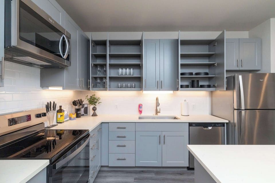 Compact kitchen fully stocked with all essentials and sleek stainless steel appliances—everything you need in a cozy space.
