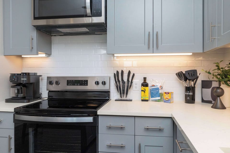 Compact kitchen fully stocked with all essentials and sleek stainless steel appliances—everything you need in a cozy space.