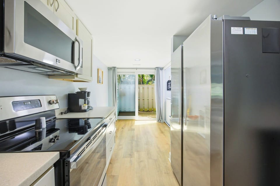 Sleek steel appliances and smooth oak floors create a bright, airy gallery for your morning coffee. Natural light pulls you toward the private patio, offering a seamless flow from the kitchen to the fresh air outside.