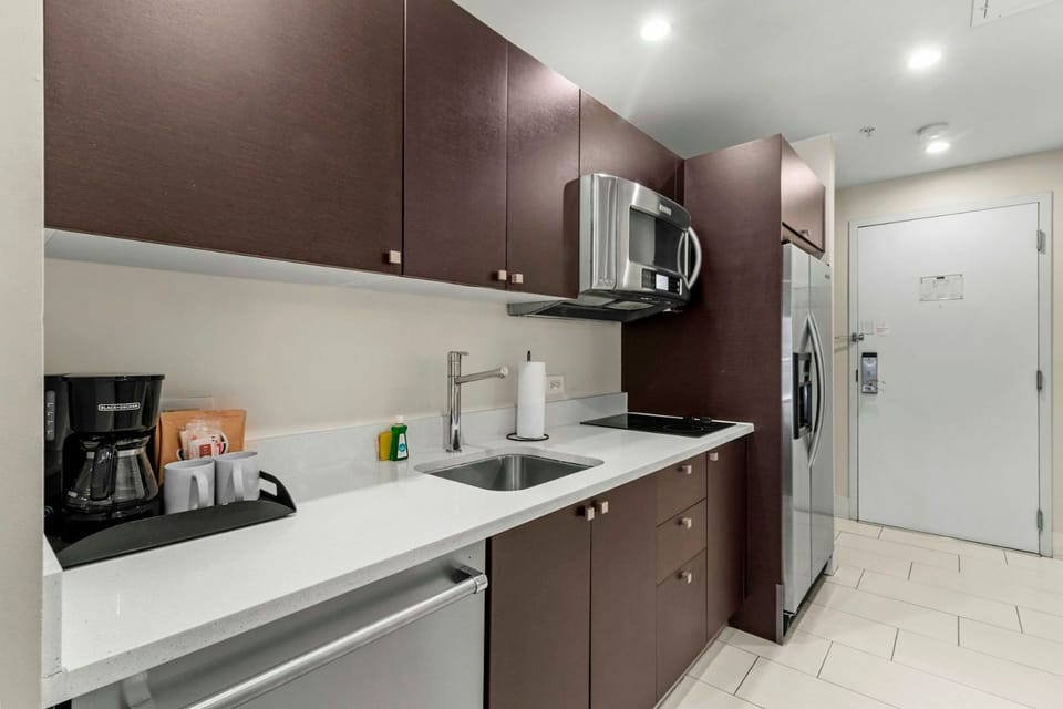 Contemporary kitchenette with modern cabinetry, sink, microwave, and essential appliances for convenient in-room dining.