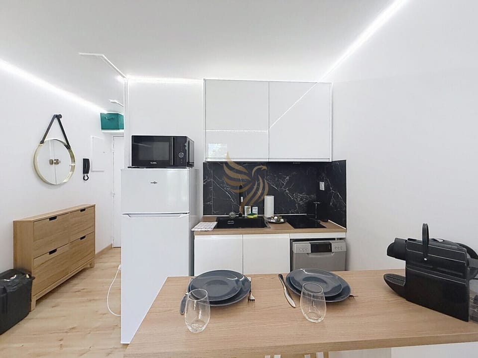 Asseyez-vous au bar en bois pour un café préparé à la machine, laissez la lumière LED douce révéler la crédence marbre: une kitchenette moderne et compacte qui transforme chaque petit repas en instant chaleureux.