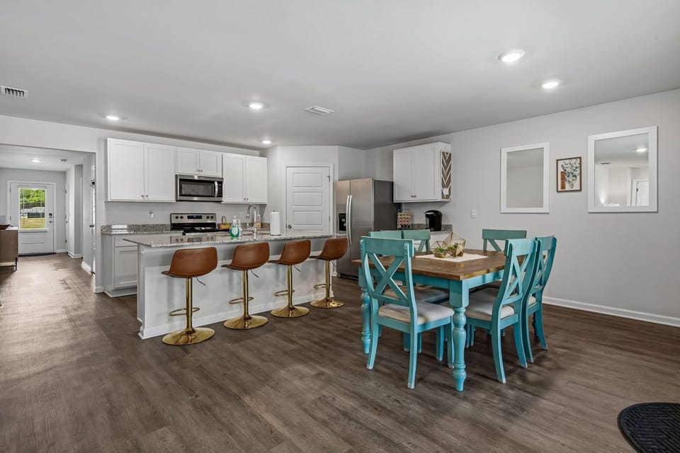 Kitchen with white cabinets, stainless appliances, granite countertop, and brown bar stools at the island