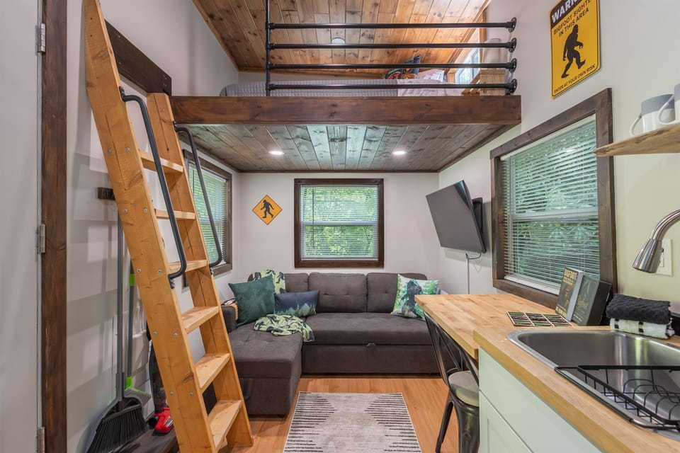 A cozy open-concept living area with loft access, comfortable seating, and Bigfoot-themed touches throughout.