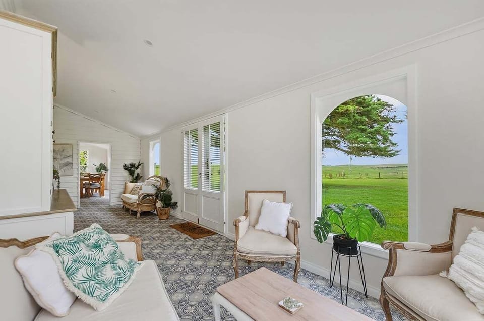 Sunroom sitting area with arched windows and greenery views.