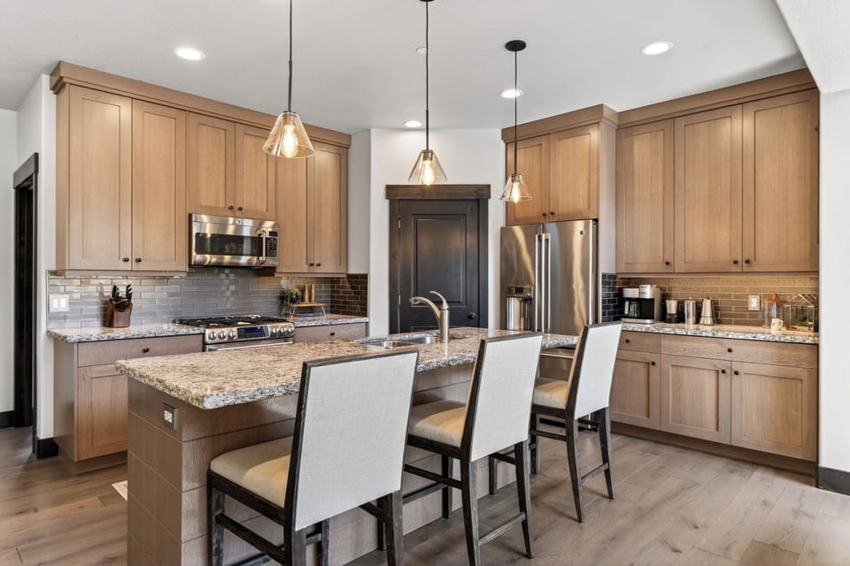 Modern chef’s kitchen featuring custom cabinetry, granite countertops, and a spacious island with seating.