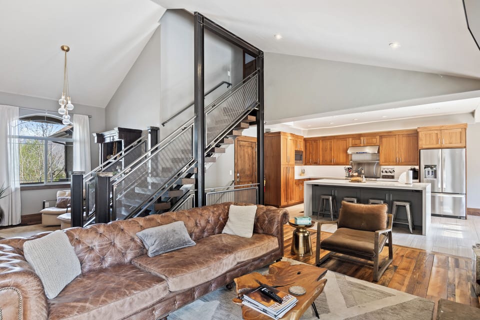 Spacious open-concept living room with comfortable seating, soaring ceilings, and seamless flow into the fully equipped kitchen.