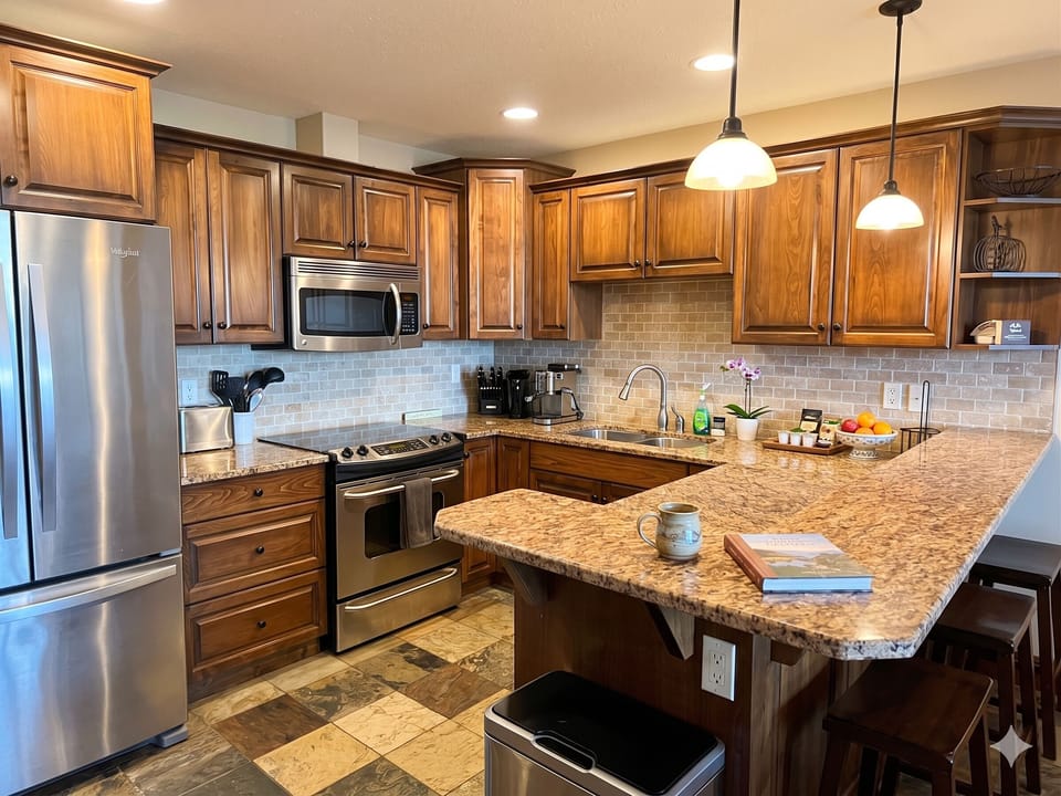 Open Plan living with a fully stocked kitchen, modern appliances, half bath, a fully equipped dining table and a kitchen bar.